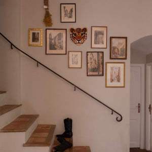 cloudy tiger wool rug by doing goods on wall amongst picture frames