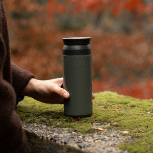 kinto travel tumbler in khaki held by a person in the woods