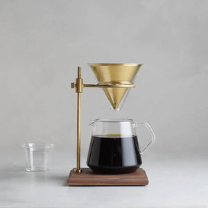 kinto coffee brewer stand with brass hardware with coffee inside the glass jar