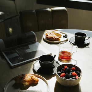 oct coffee cup in black by kinto on breakfast table with food and magazine