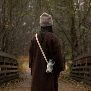 woman carries travel tumbler in the woods