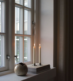 silver candle holder with white candles next to window inside the house