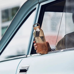 water bottle in amber by kinto held by hand in car